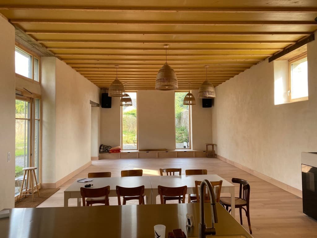 Grande salle lumineuse aux poutres de bois où se déroulent les stages de yoga de Sophie Duthu