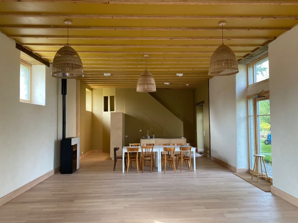 Salle de pratique des Passages Suspendus : parquet clair, poêle à bois et grandes ouvertures sur le jardin